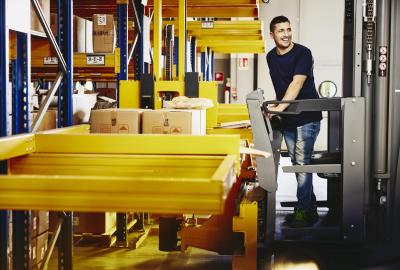 Smiling man standing on a forklift.