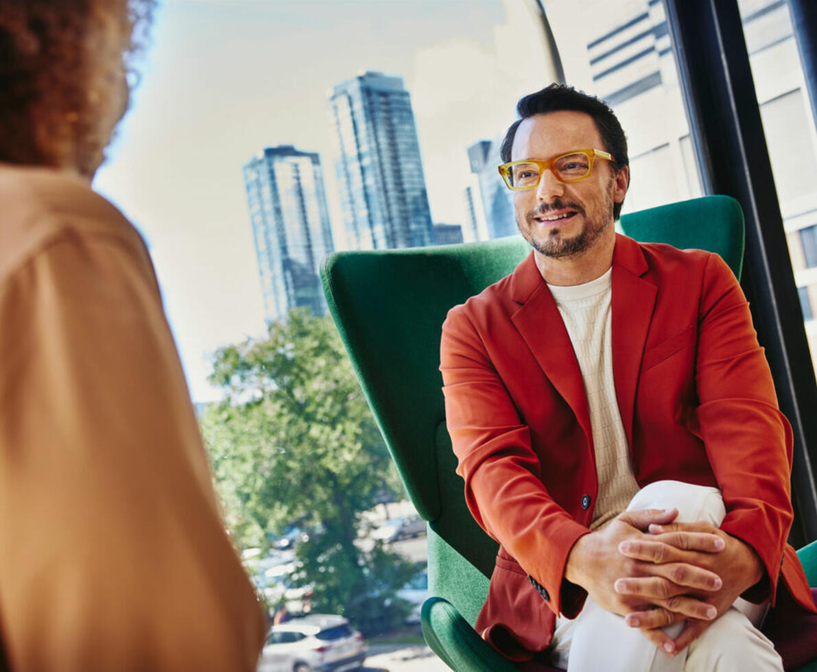 smiling man with glasses sitting on a chair