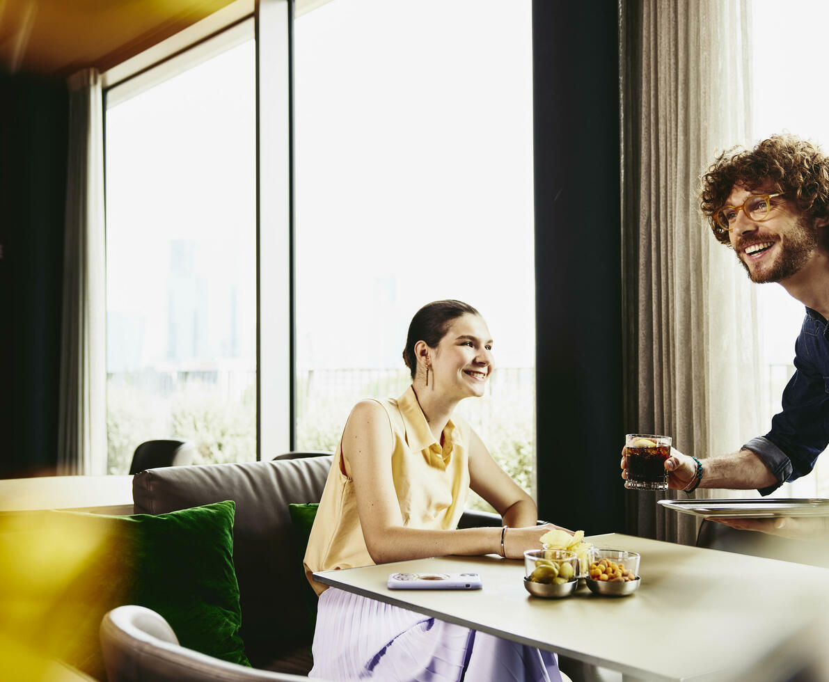 Waiter serving a drink to female sitting at a table.
Waiter serving a drink to female sitting at a table.
