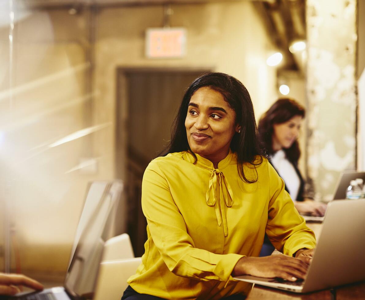 Woman working on her laptop while having a conversation