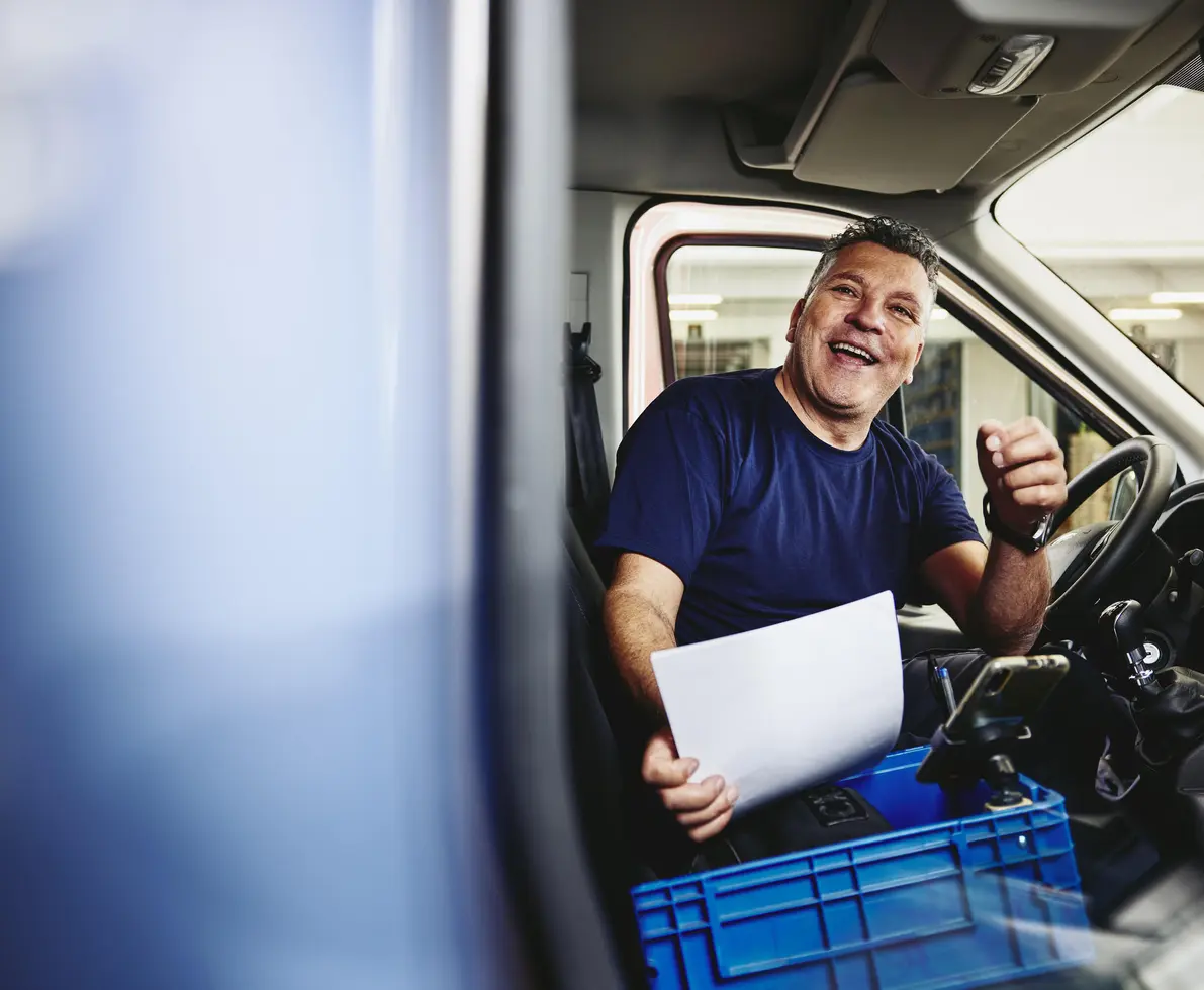 bărbat zâmbitor așezat în interiorul unui camion