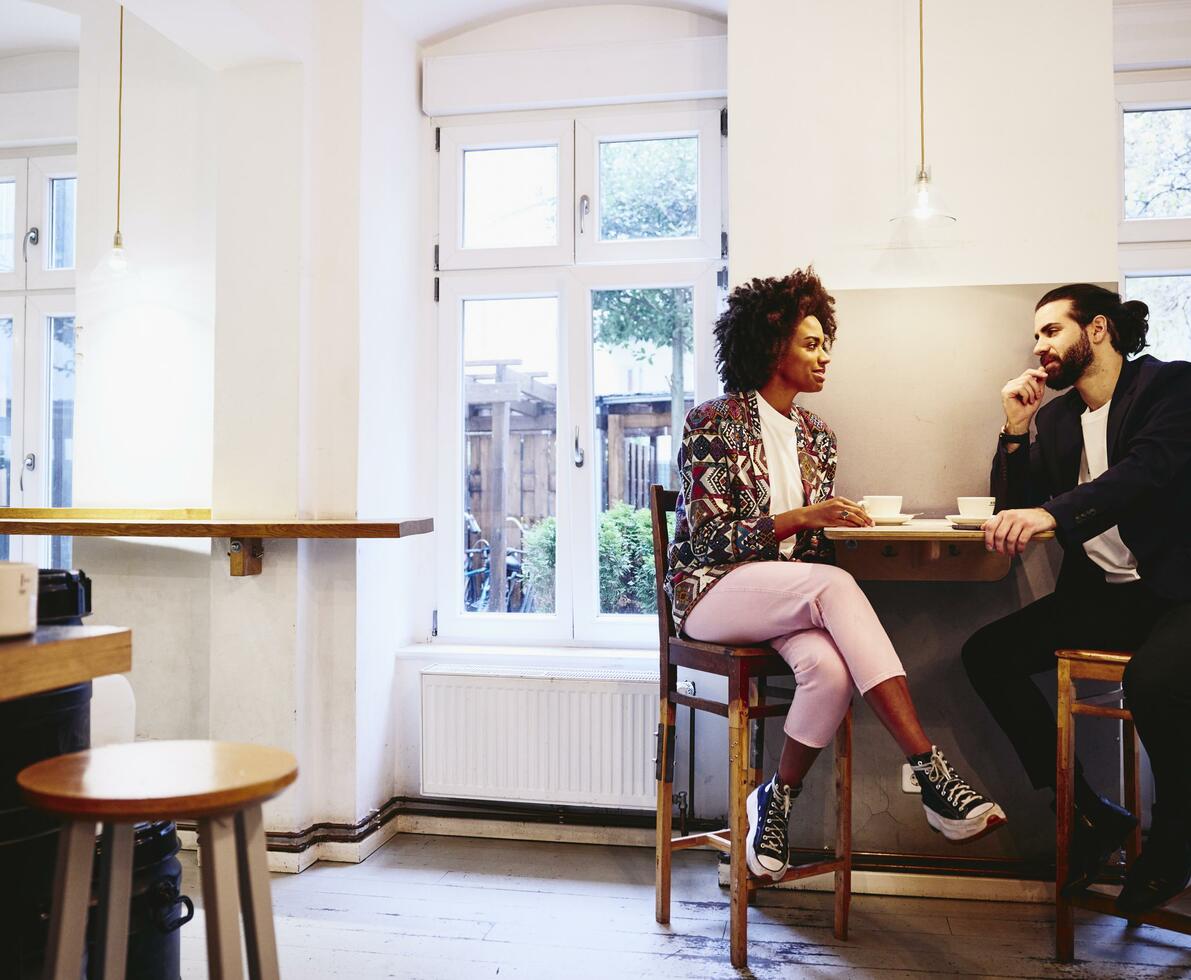 Woman and man sitting at a table with coffee. Having a conversation.