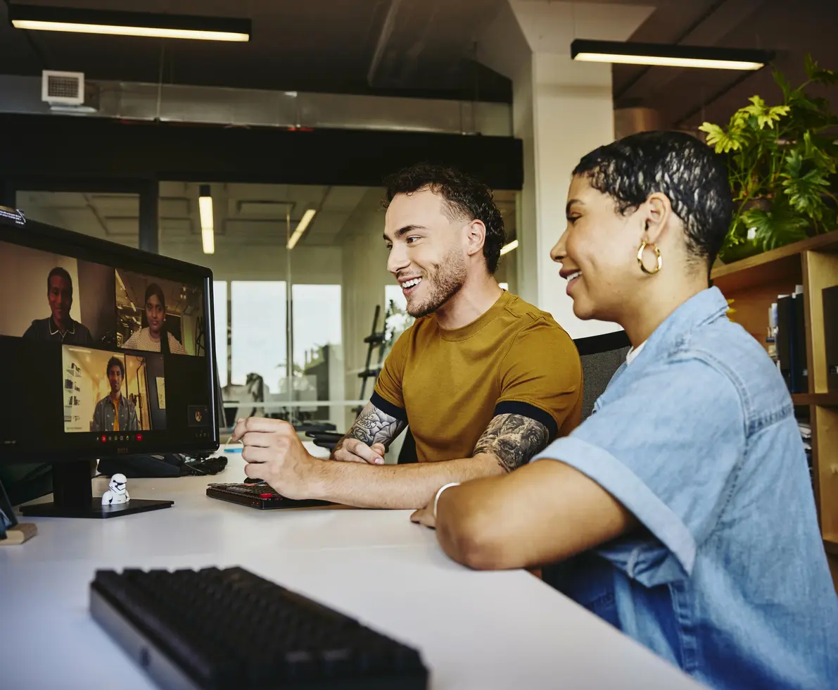 Male and female sitting behind a computer in a video meeting
