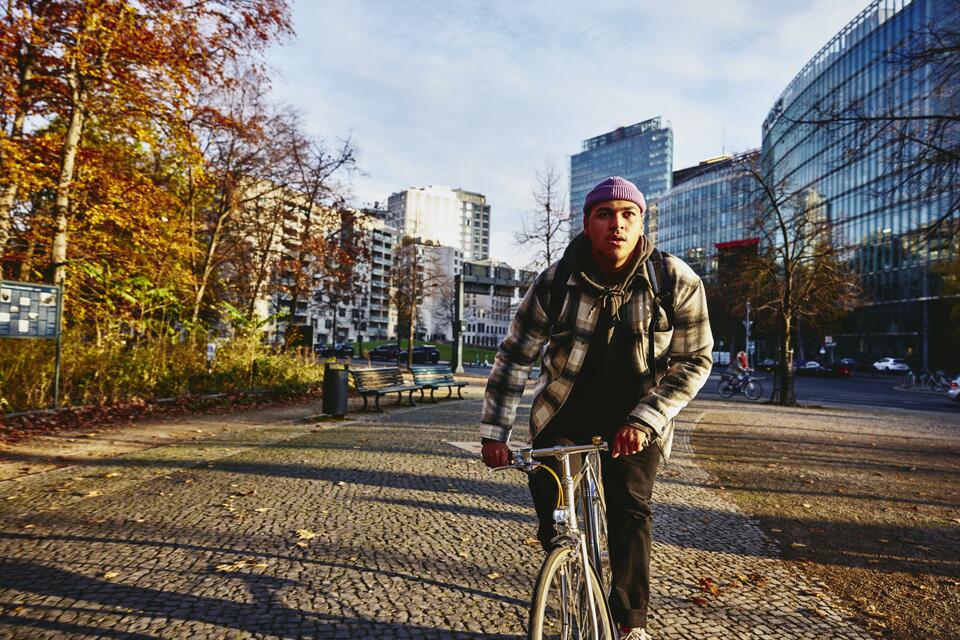 Cycling man, autumn trees and office buildings on the background.